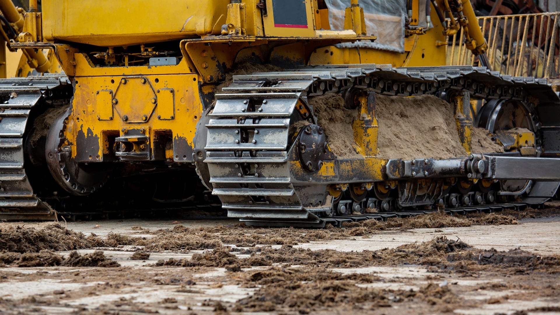 Courses > NPORS Plant Training > Header > Background Close-up of the tracks on heavy construction machinery operating on muddy ground.