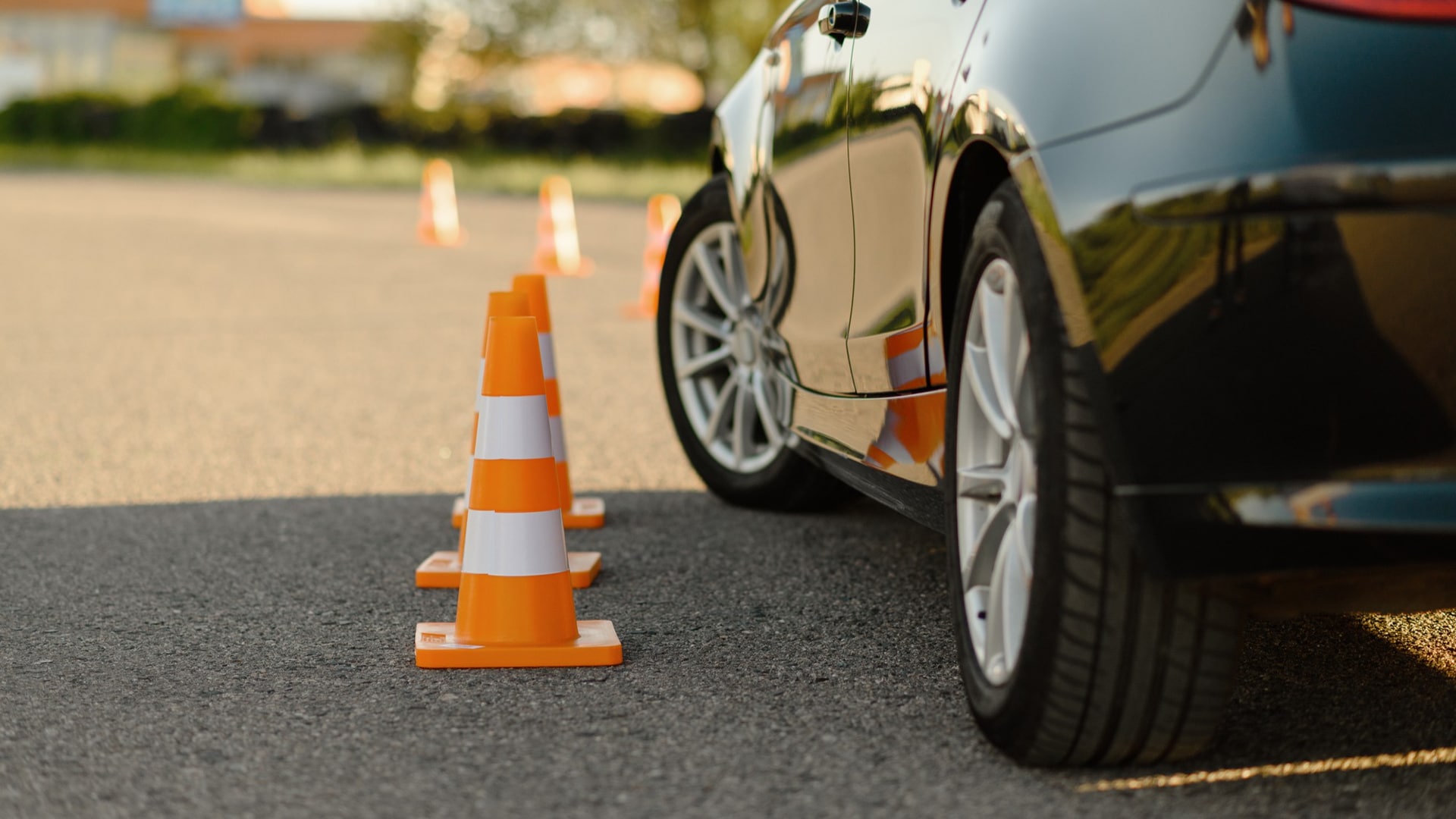 Courses > Vehicle Safety > Header > Background Car manoeuvring through traffic cones during a practical driving training session.