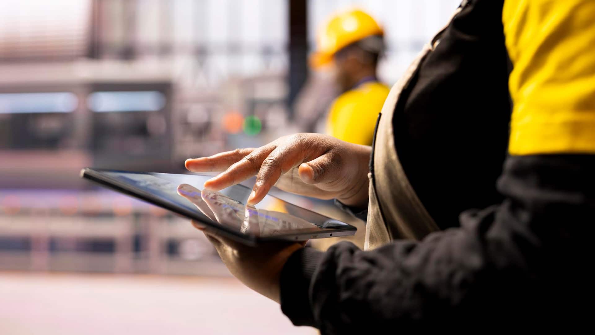 Resources > Insights > Header > Background Worker using a tablet to access digital information in an industrial workplace.